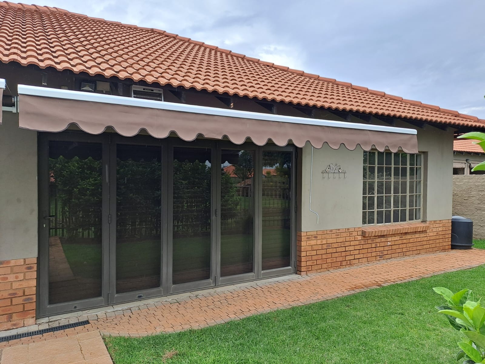 Retractable folding-arm awning over a patio door